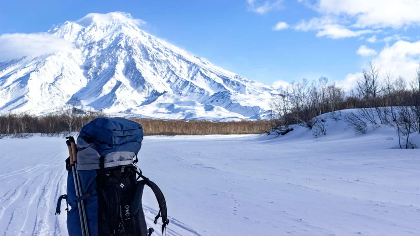 A blue tourist backpack stands on the snow