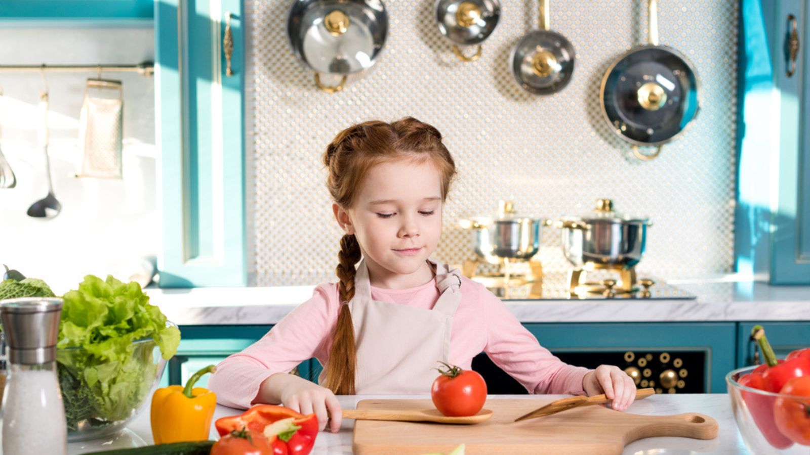 Adorable little girl in apron cooking in kitchen