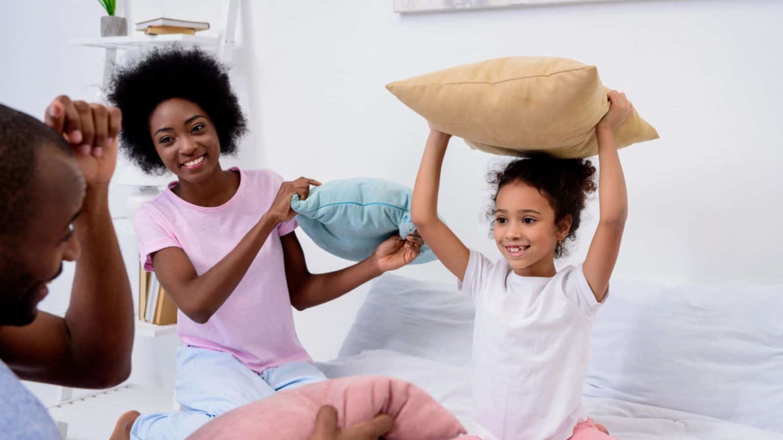 African american parents and daughter playing with pillows at home