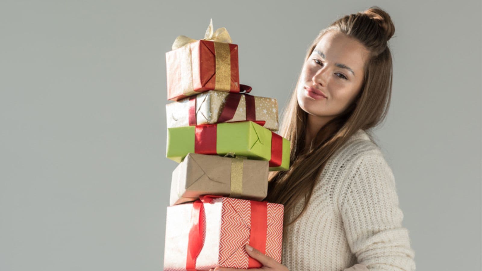 Attractive woman in fashionable winter outfit holding gift boxes
