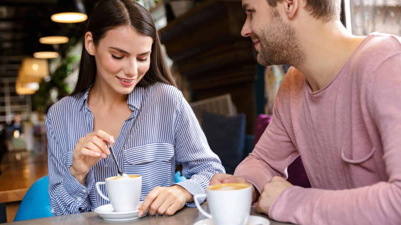 Attractive young couple in love having lunch at the cafe indoors, drinking coffee
