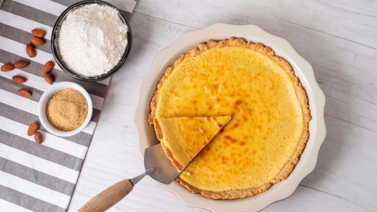 Baked sweet cheesecake with cooking ingredients on kitchen