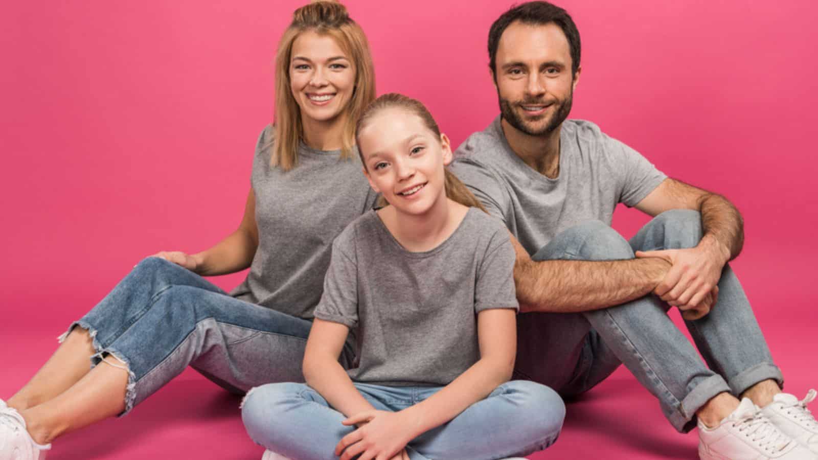 Beautiful family with happy daughter sitting on pink