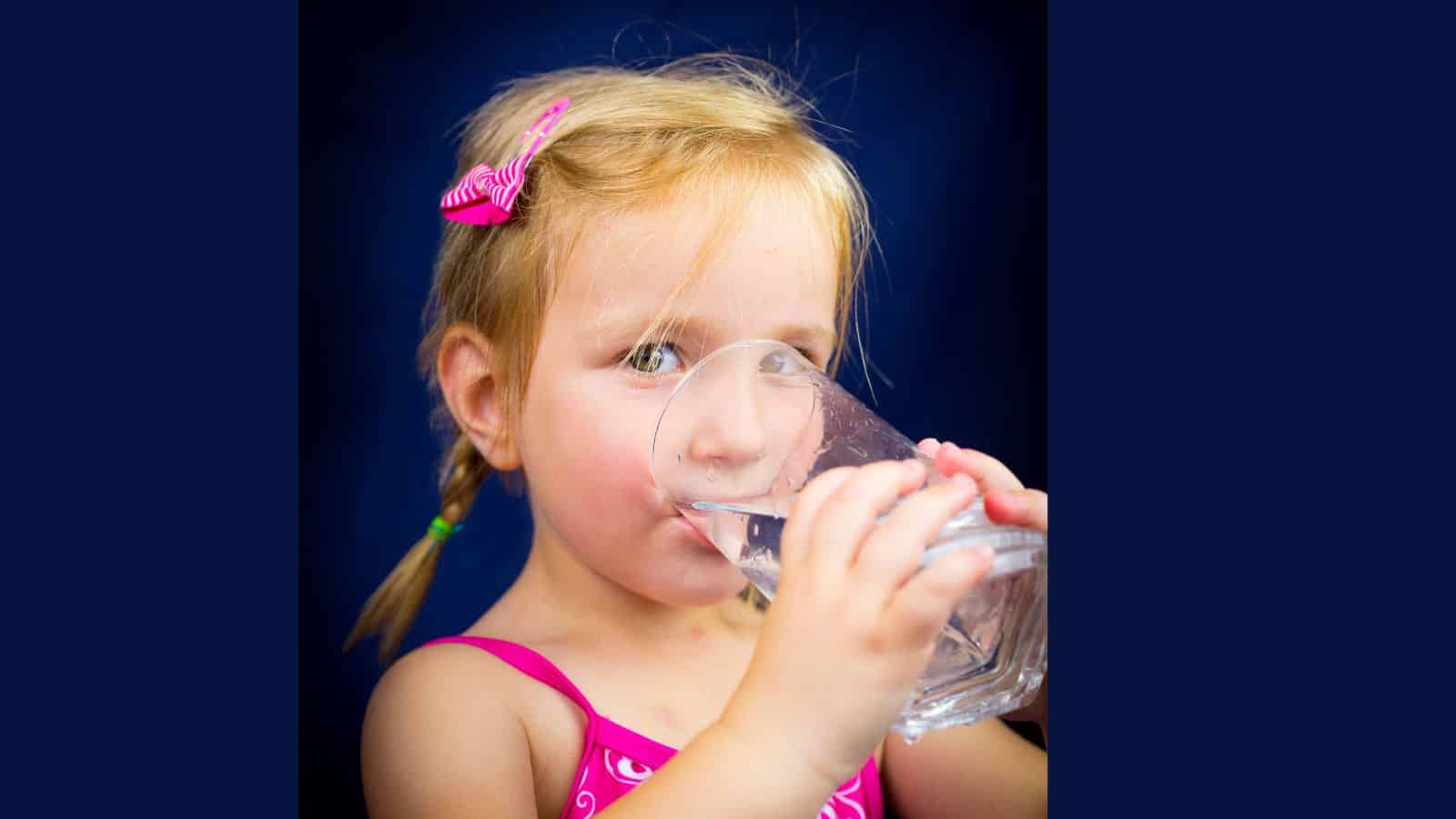 Beautiful little blond girl drinking water 