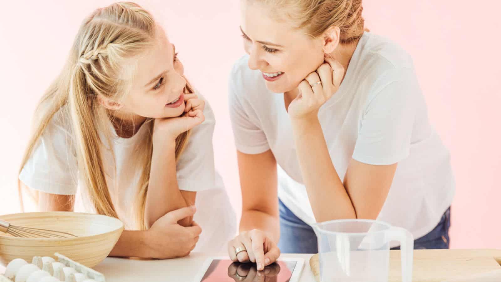 Beautiful mother and daughter in white t-shirts using tablet