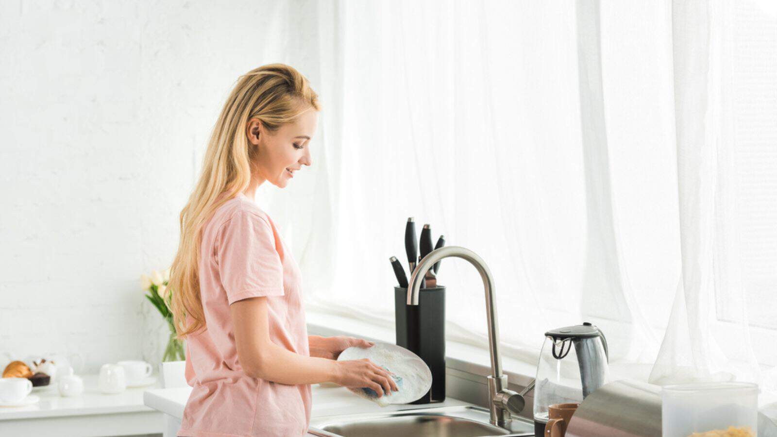 Beautiful woman washing dishes at kitchen in morning