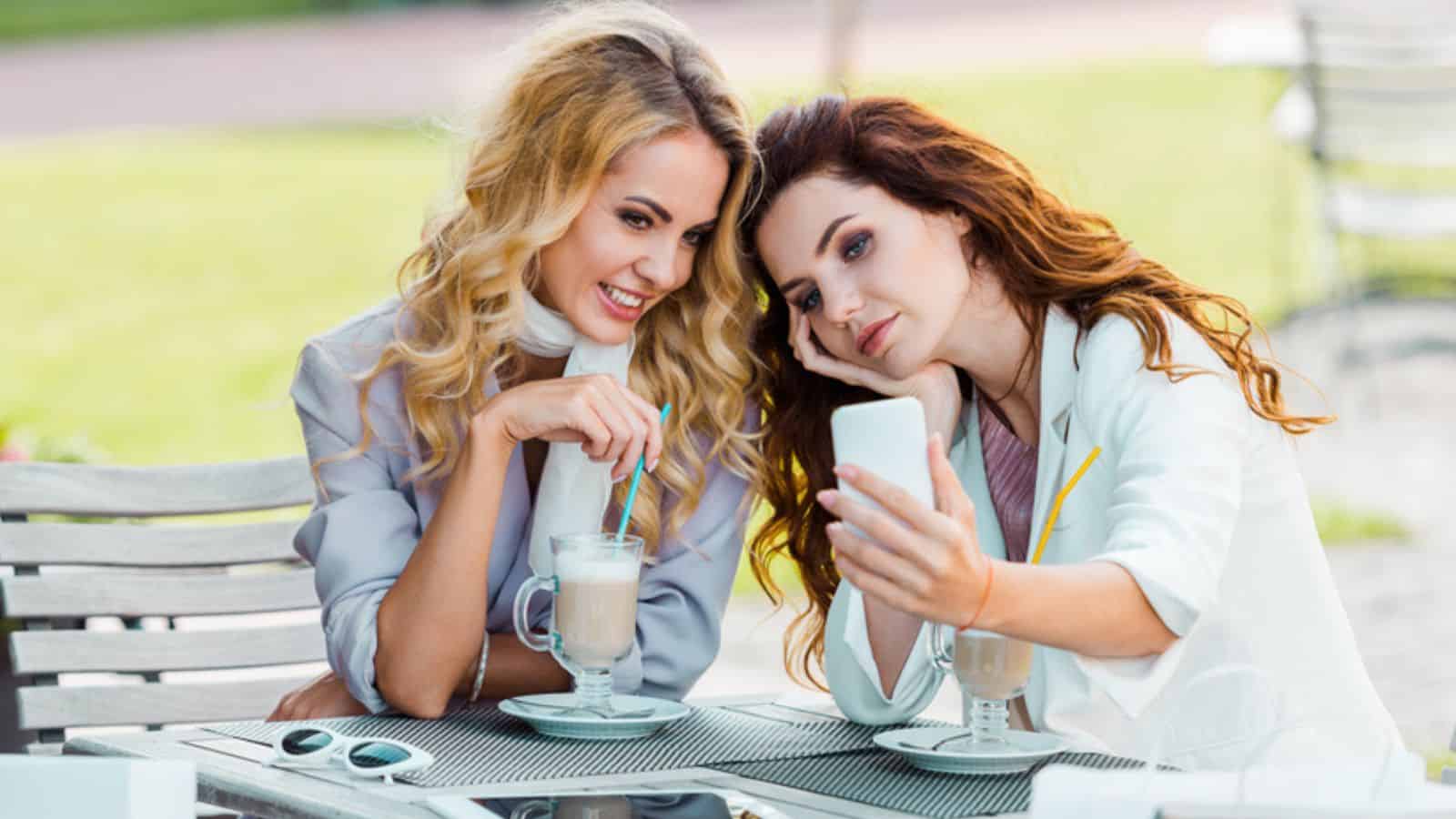 Beautiful young women taking selfie while sitting in cafe