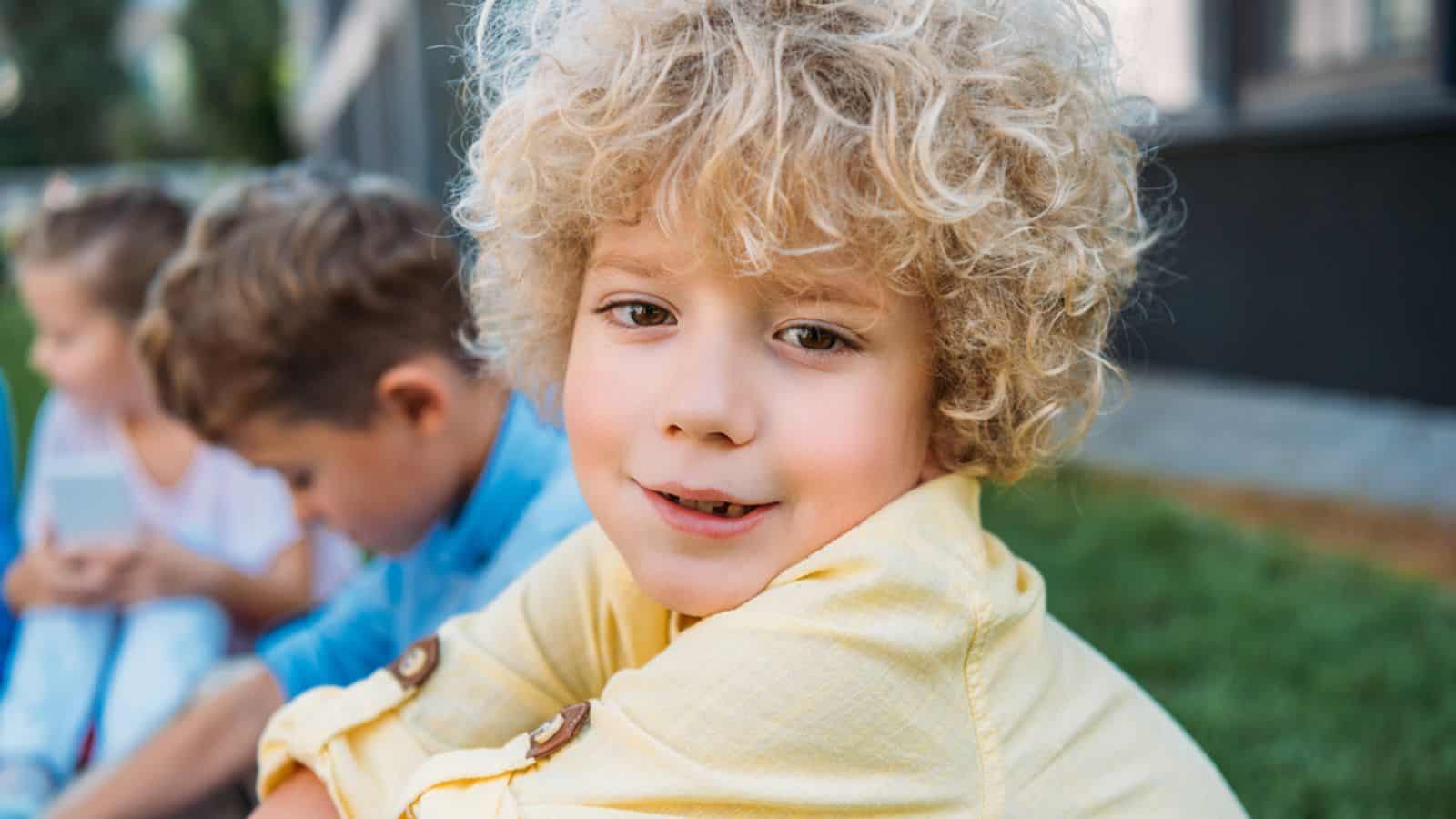 Close-up portrait of adorable curly schoolboy sitting