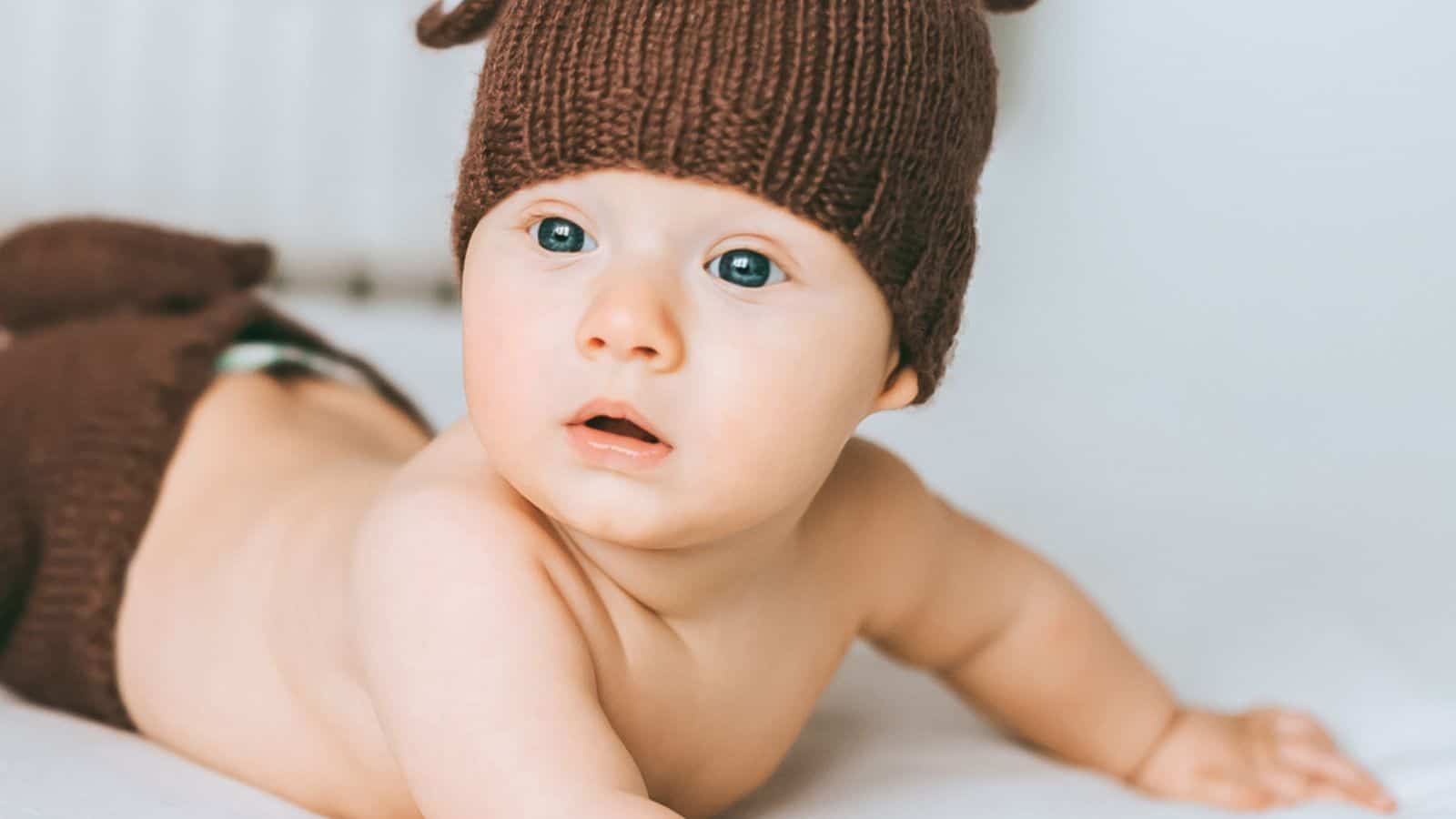 Close-up portrait of adorable infant child in knitted deer costume in bed
