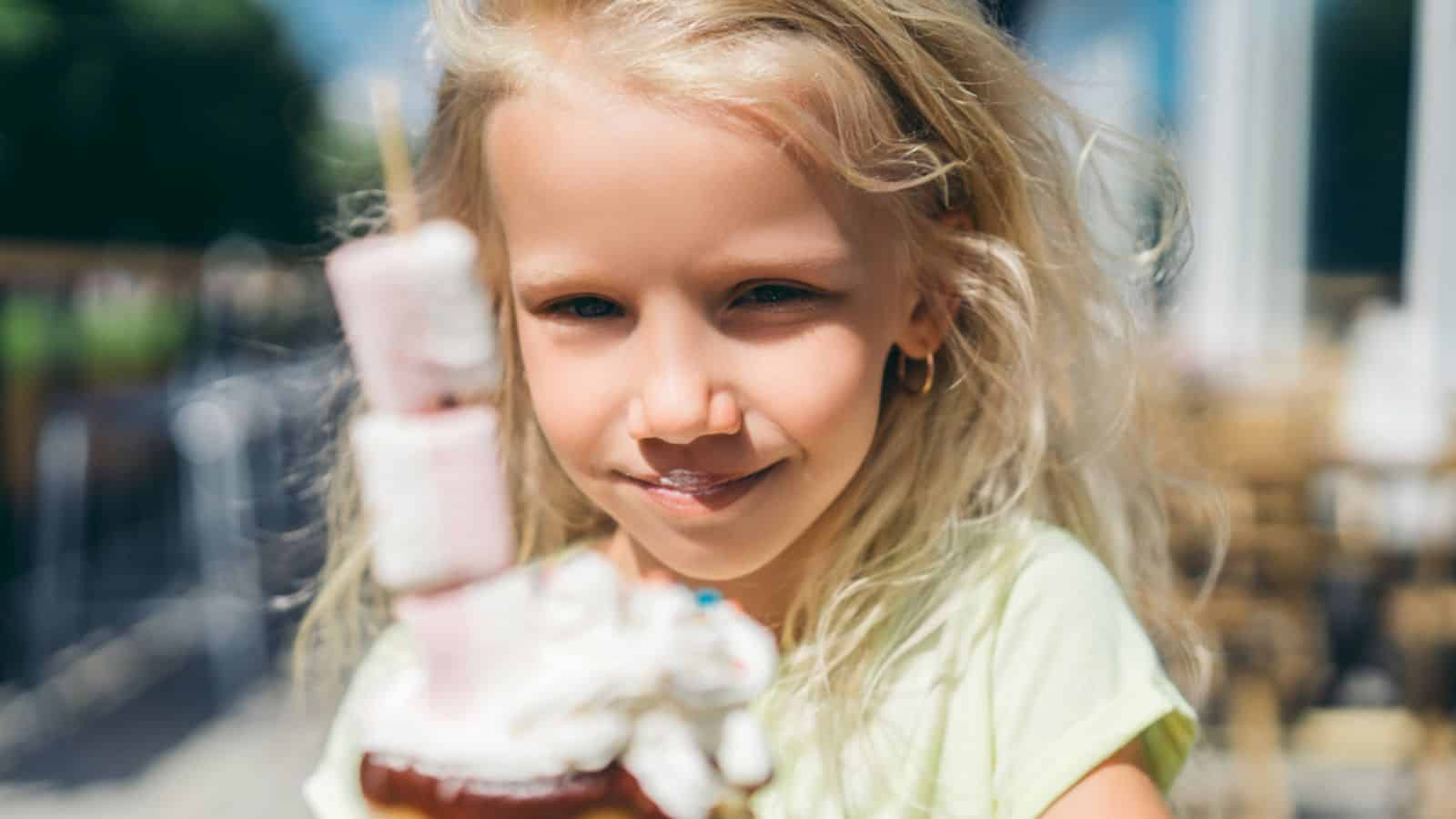 Close up portrait of adorable little kid eating tasty dessert