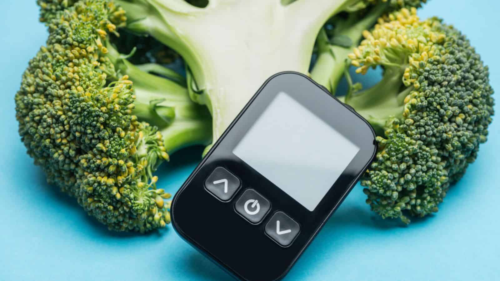 Close up view of glucometer with broccoli on blue background