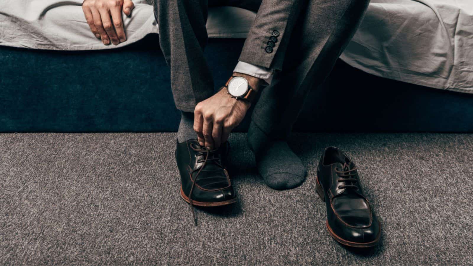 Cropped image of businessman putting on shoes in bedroom