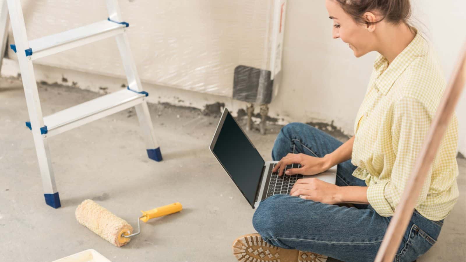 Cropped shot of smiling young woman using laptop while sitting at new home