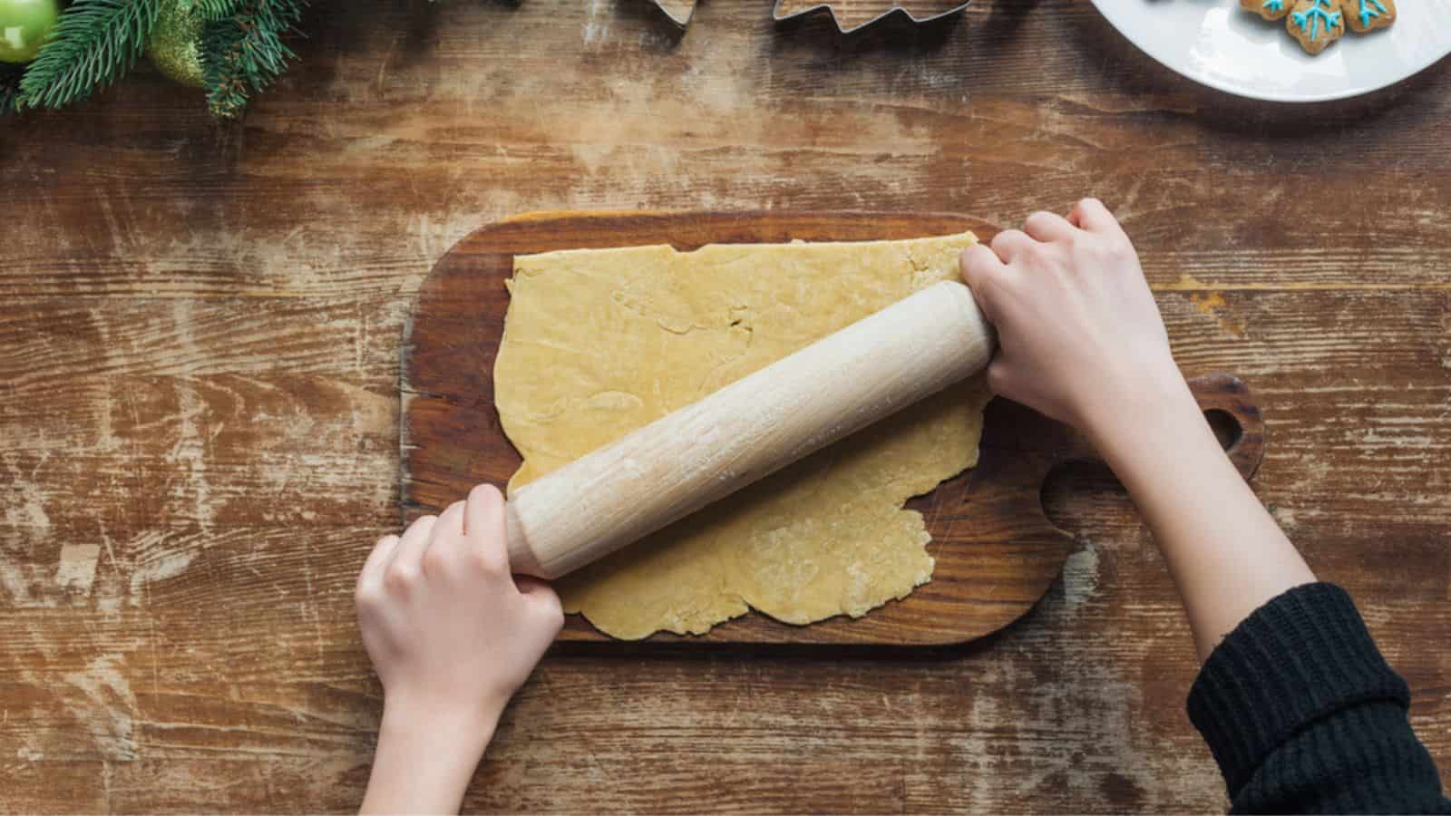 Cropped shot of woman rolling dough with rolling pin