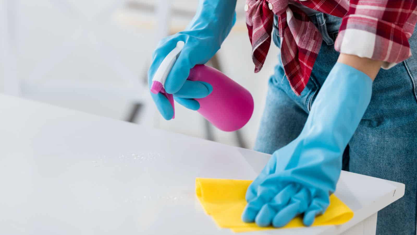 Cropped view of african american woman cleaning table in blue rubber