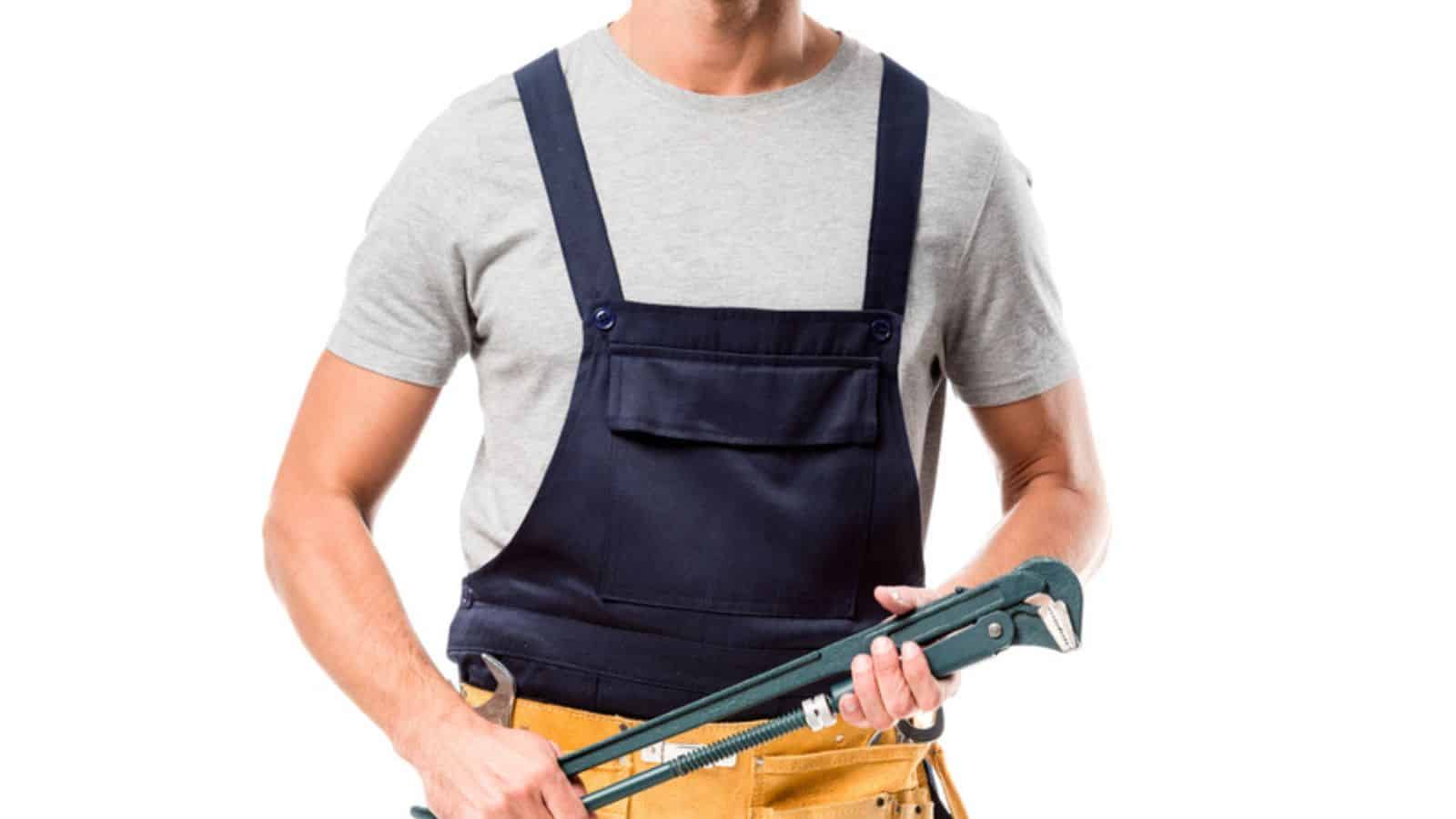 Cropped view of worker in overalls holding pipe wrench