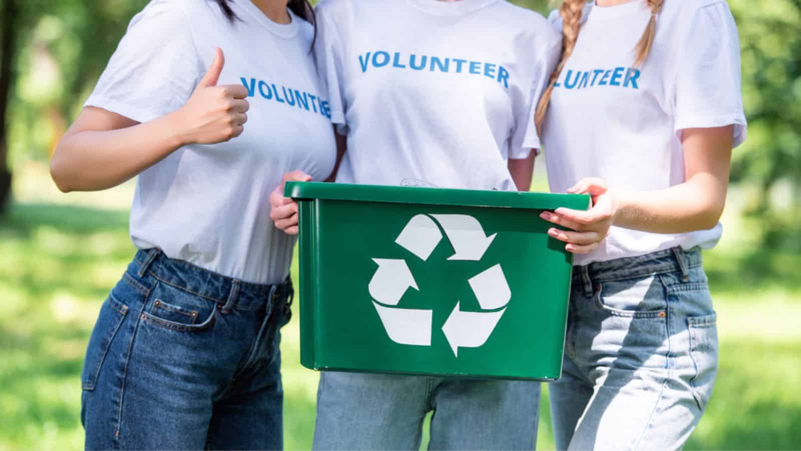 Cropped view of young volunteers with green recycling box