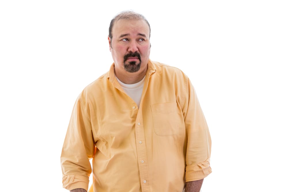 Distrustful sceptical middle-aged man with a goatee standing looking sideways to the right of the frame with a speculative look, part of a series on body language, isolated on white