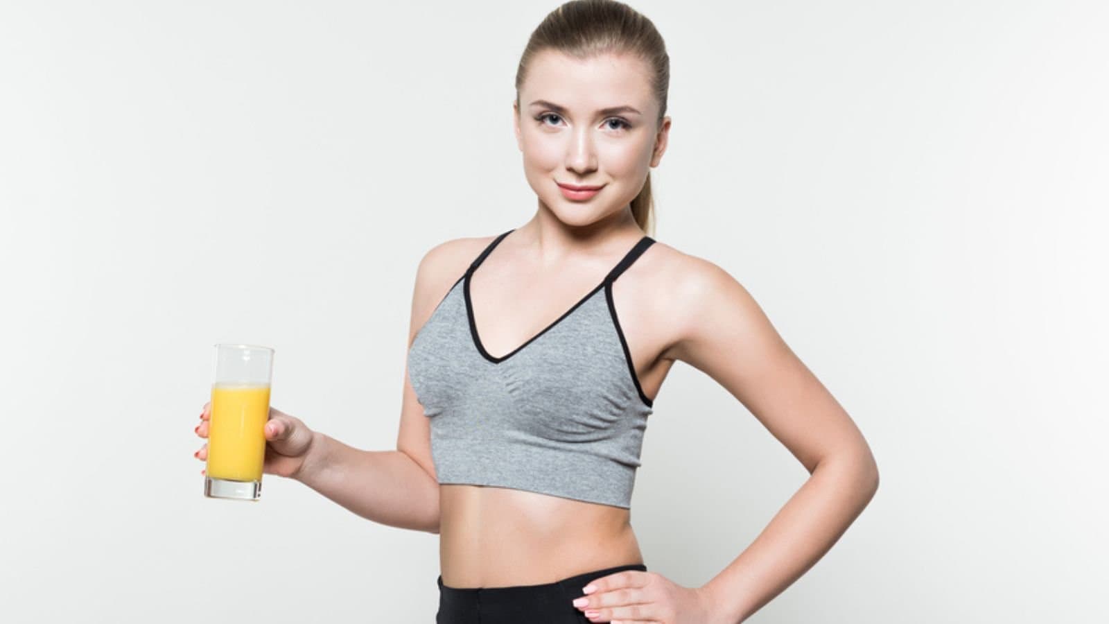 Fit girl holding glass with juice isolated on white