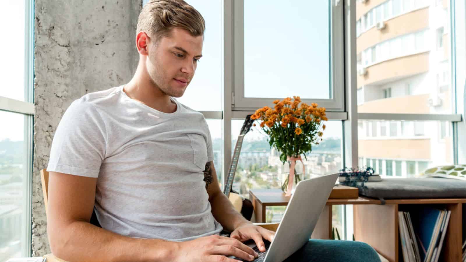 Focused man in armchair using laptop at home
