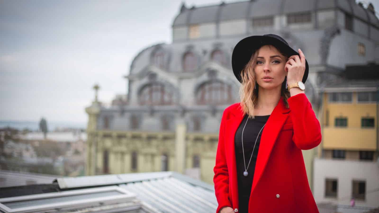 Girl in red and with black hat posing on the roof of old city