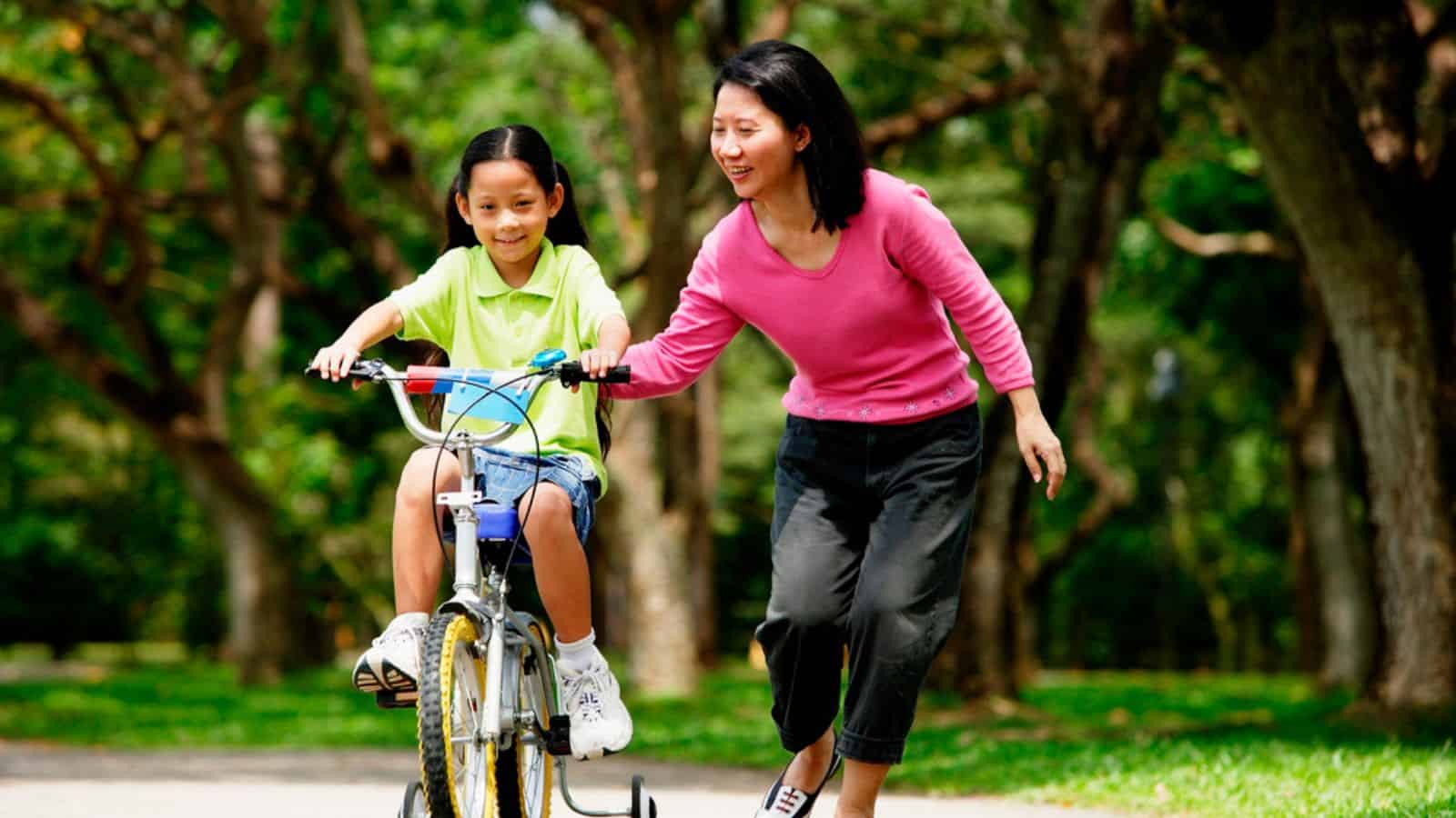 Girl training bicycle with mom