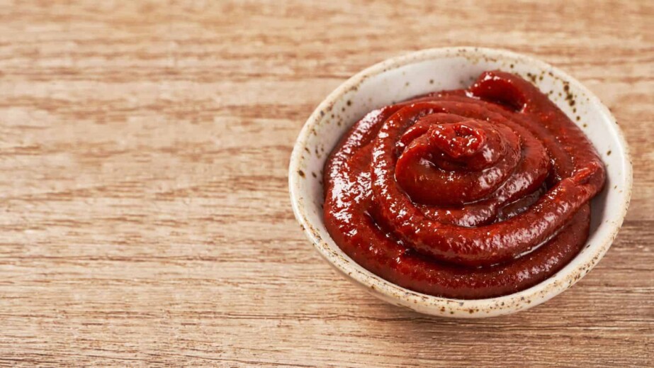 Gochujang or Korean red chili paste in a ceramic bowl on wood background