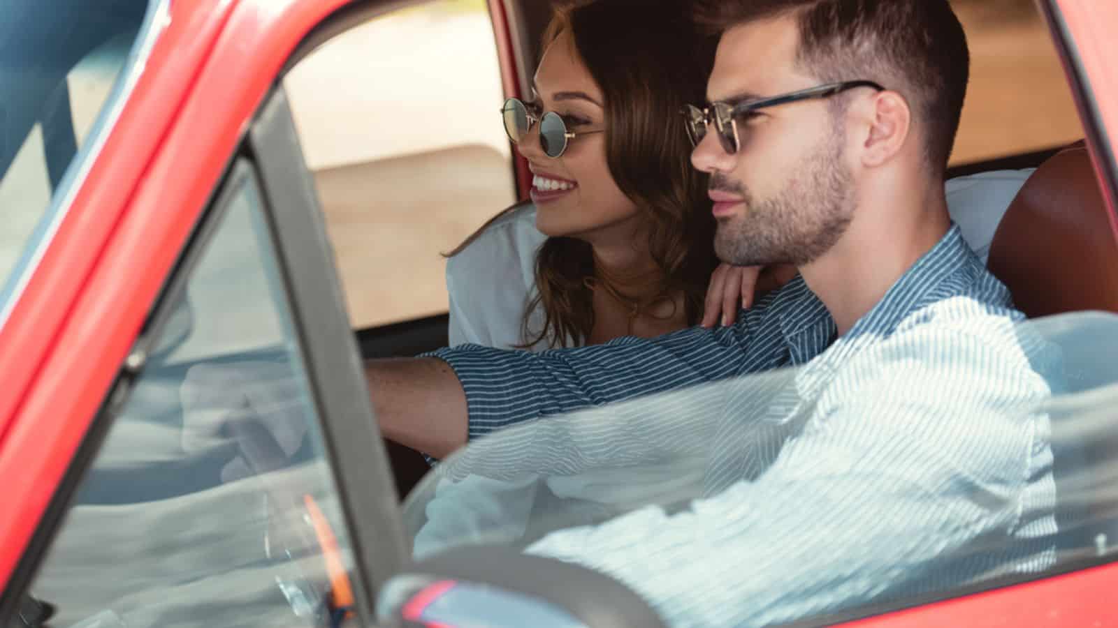 Handsome man driving car with his happy girlfriend