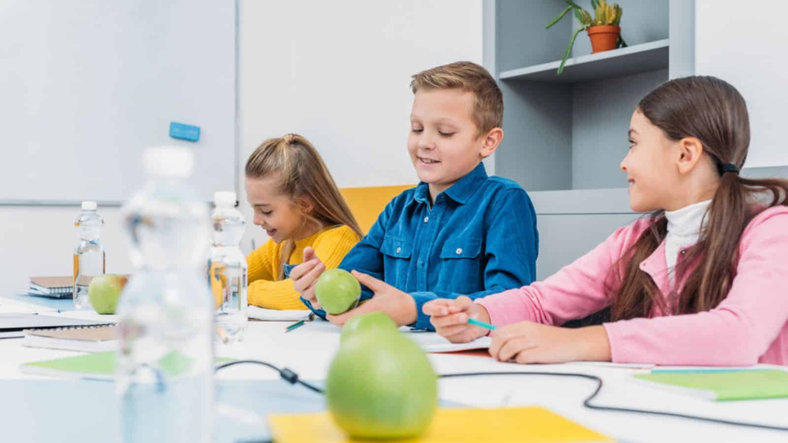 Happy children sitting at desk in classroom
