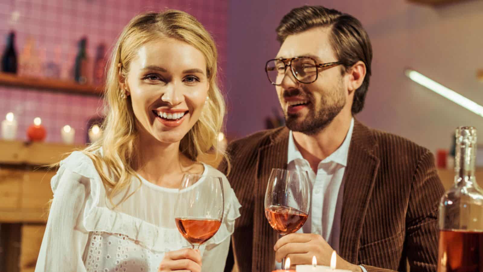 Happy couple with wine glasses celebrating and having date