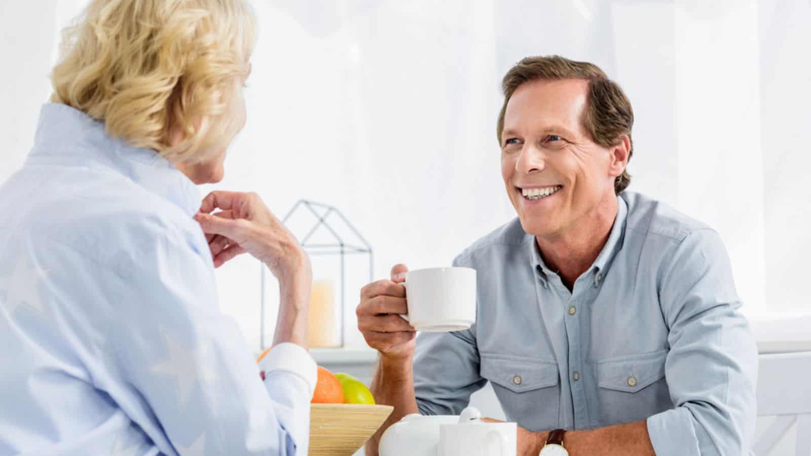 Happy elderly couple drinking tea and smiling each other at home