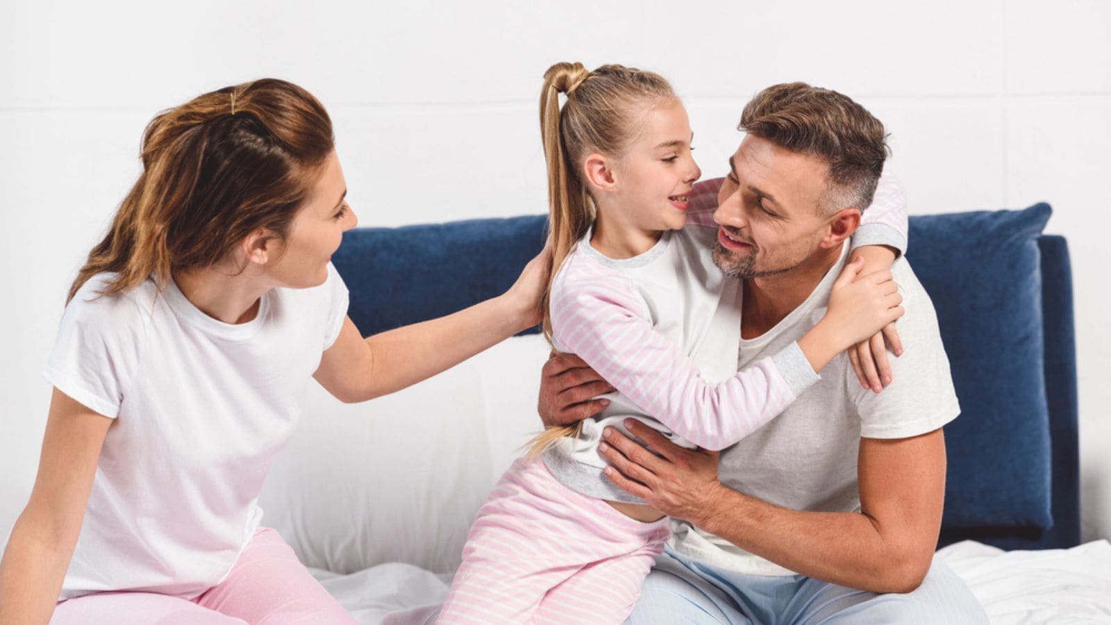 Happy family in pajamas hugging in bed
