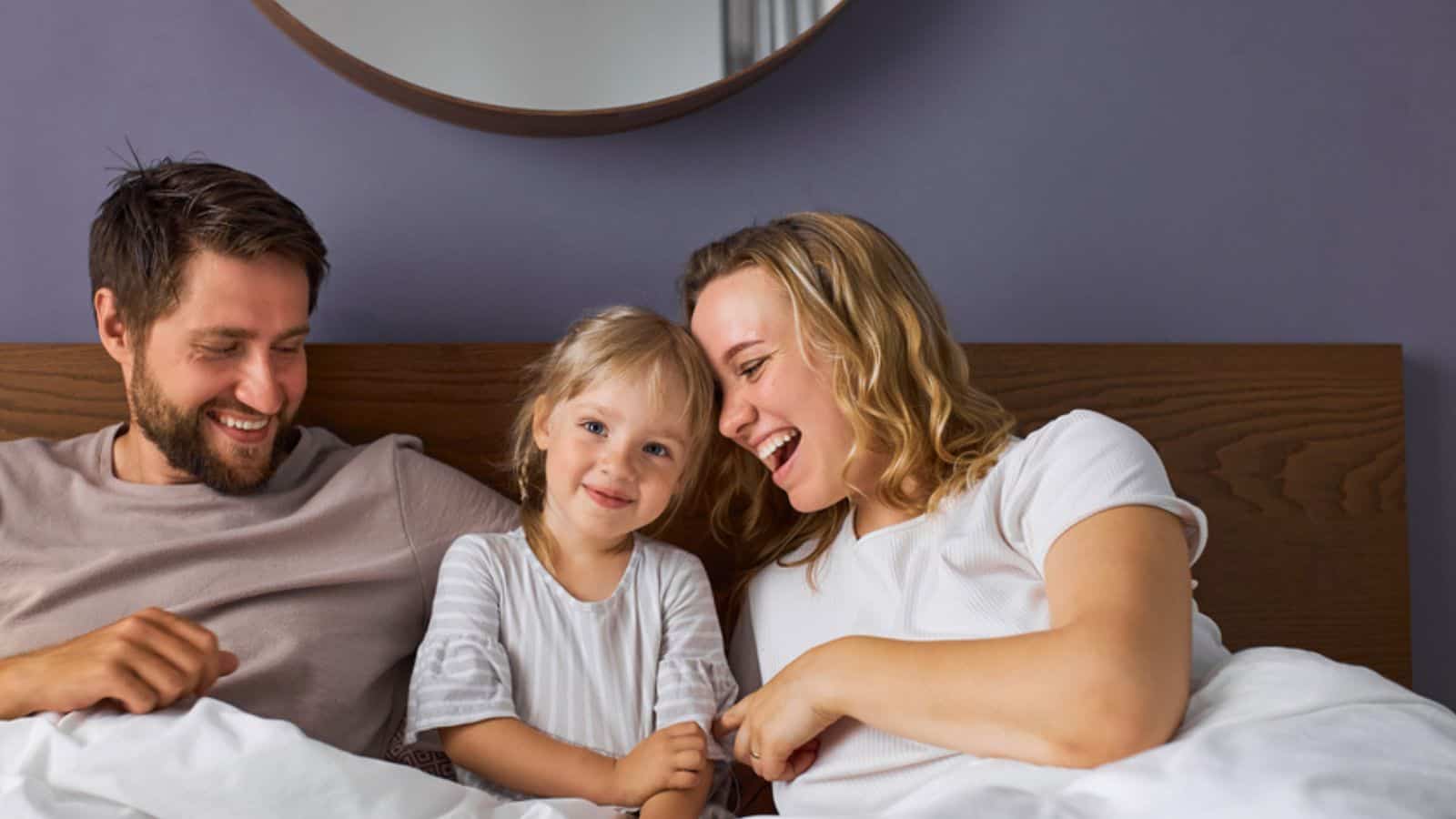 Happy family with child girl laugh lying on bed in the morning
