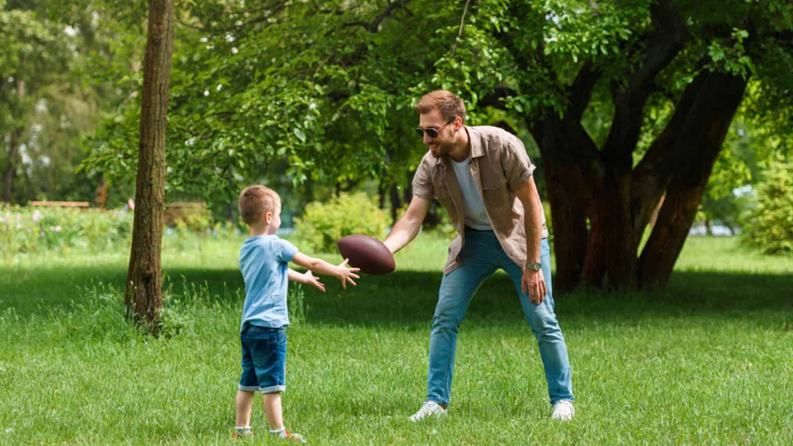 Happy father and son playing american football at park