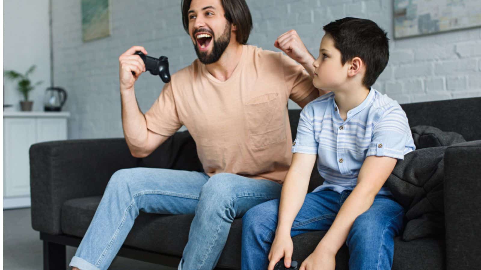 Happy father and son playing video games together at home