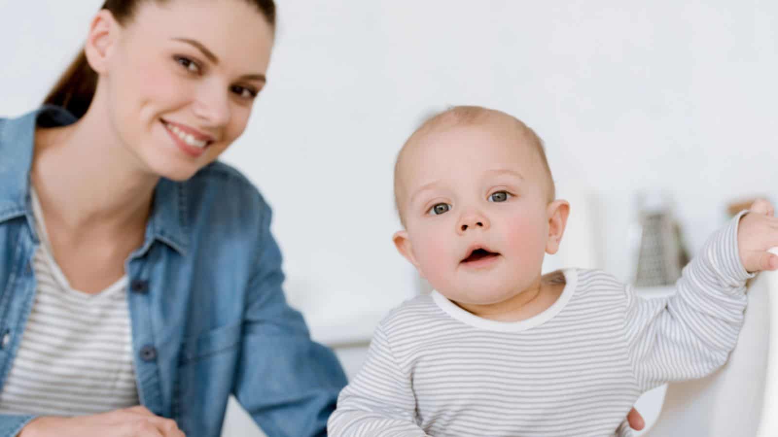 Happy mother with little baby boy sitting on kitchen