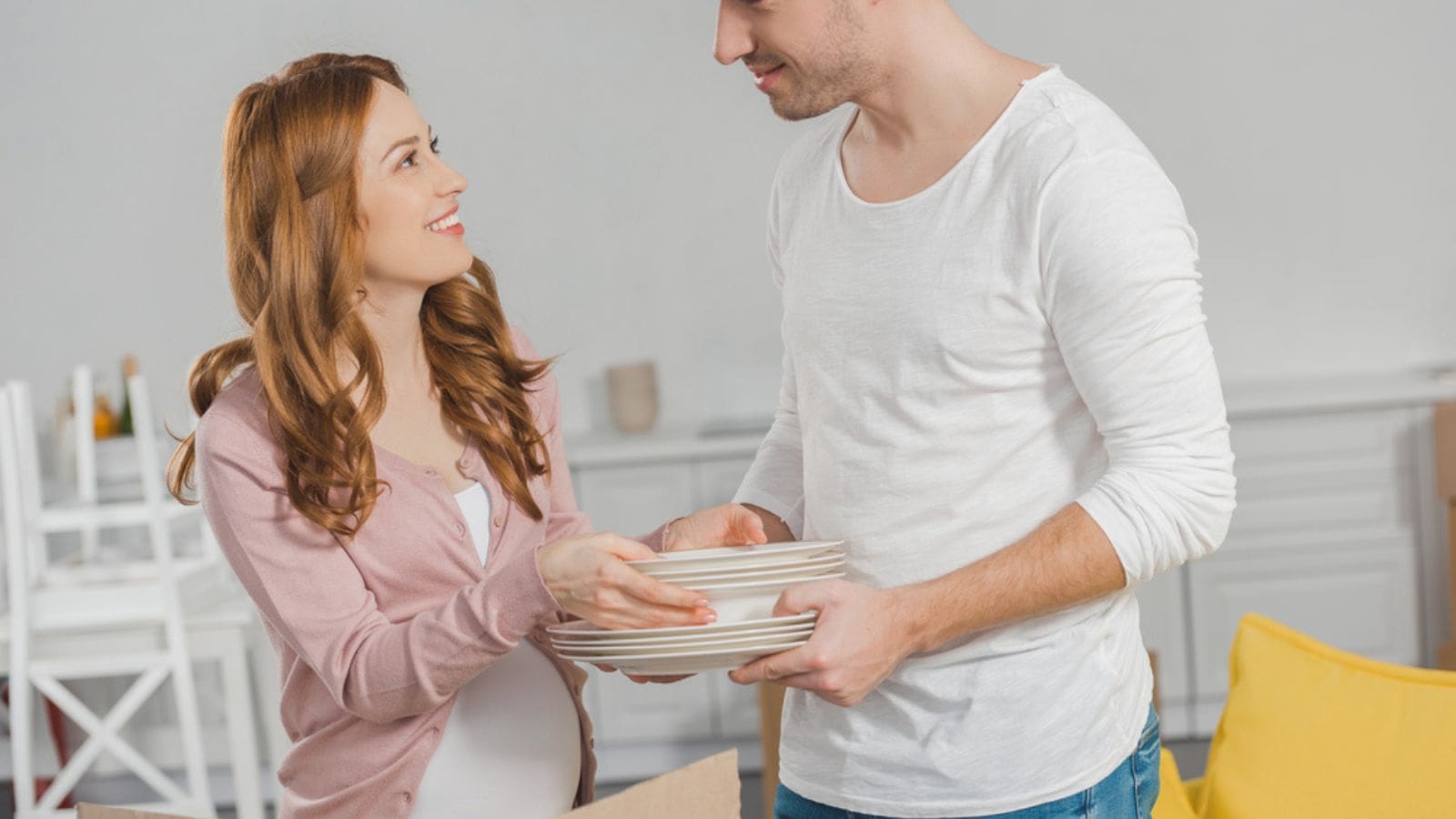 Happy pregnant couple holding dishware and smiling each other