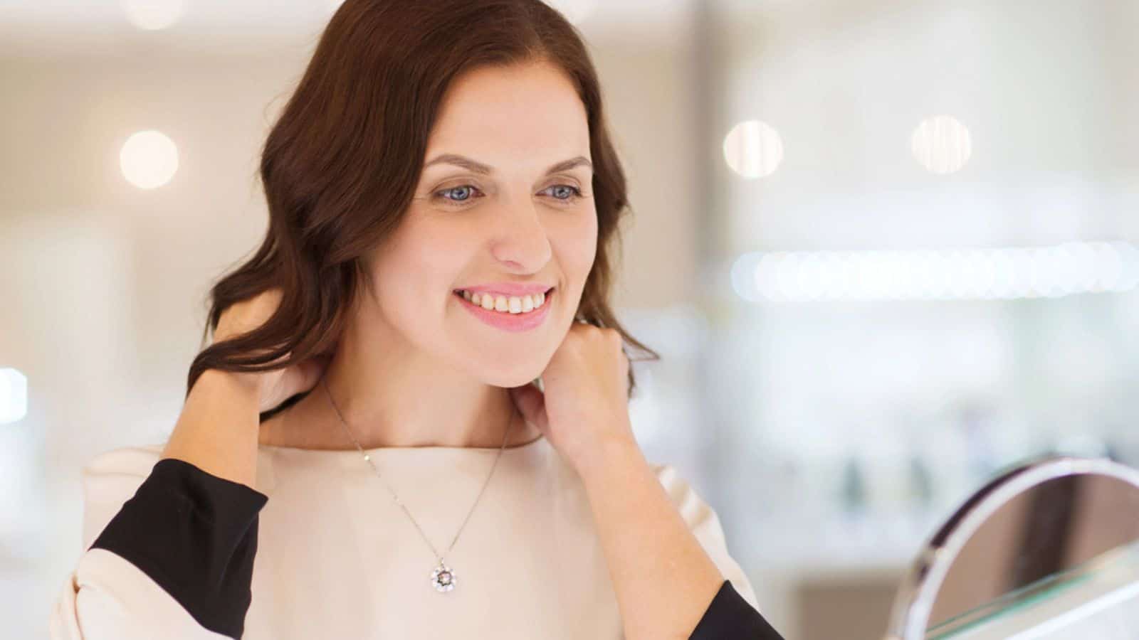 Happy woman choosing pendant at jewelry store
