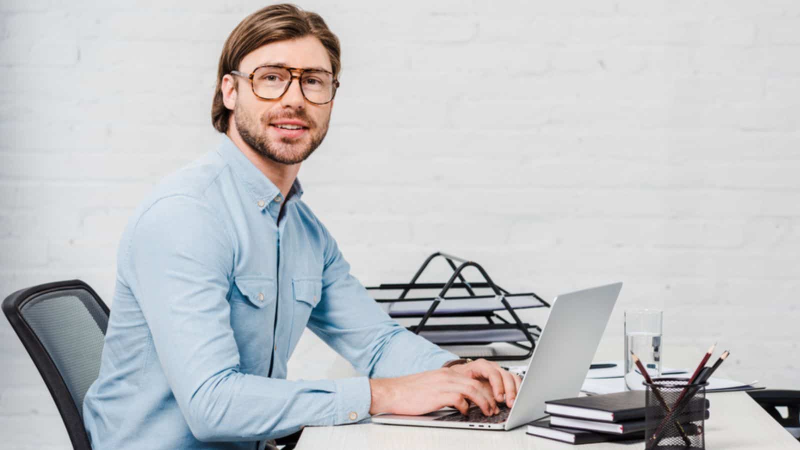 Happy young businessman working with laptop at modern office