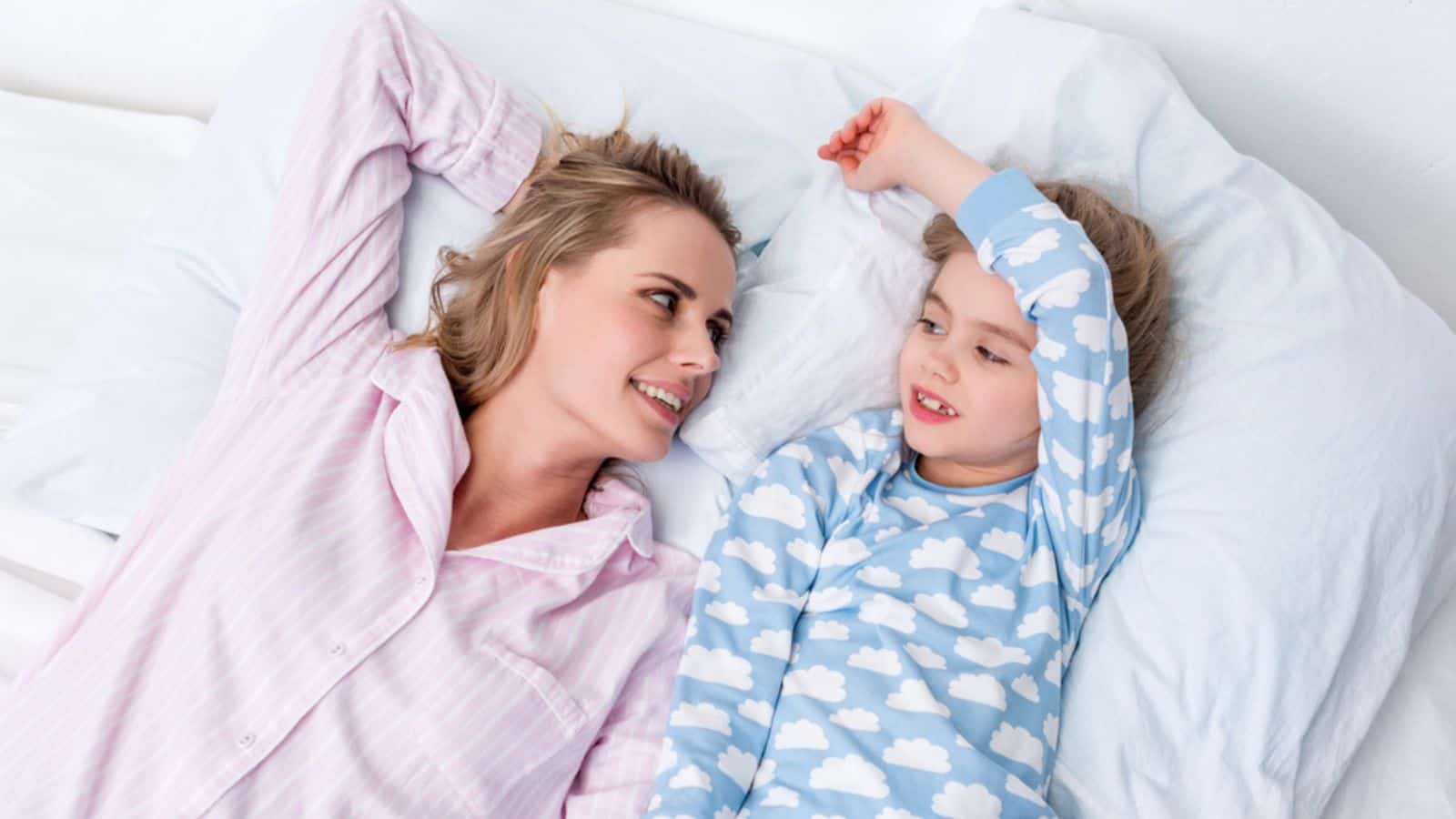 High angle view of happy mother and daughter lying on bed at home