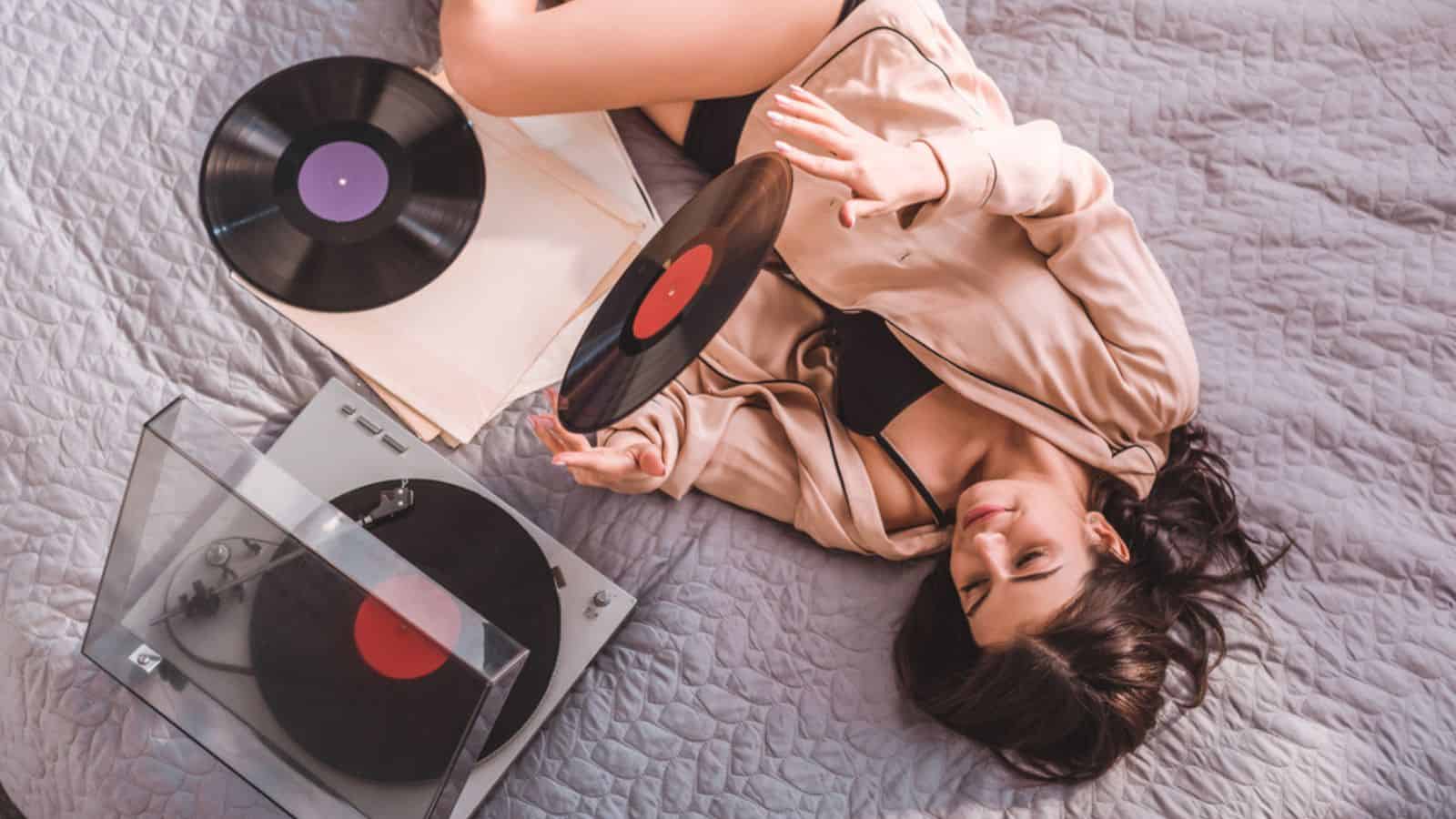 High angle view of woman laying on bed and listening vinyl