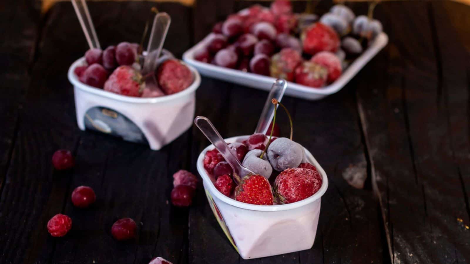Homemade fresh yogurt Healthy sweet dessert on dark rustic wood frozen fruits