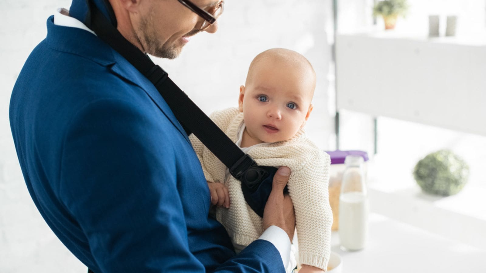 Infant daughter in babycarrier with father in suit