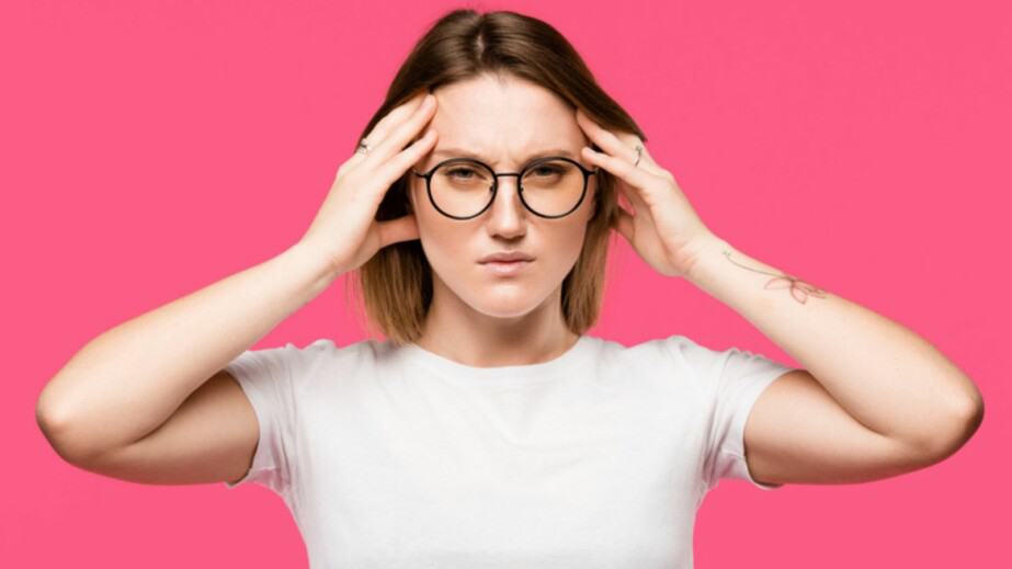 Irritated woman in eyeglasses having headache