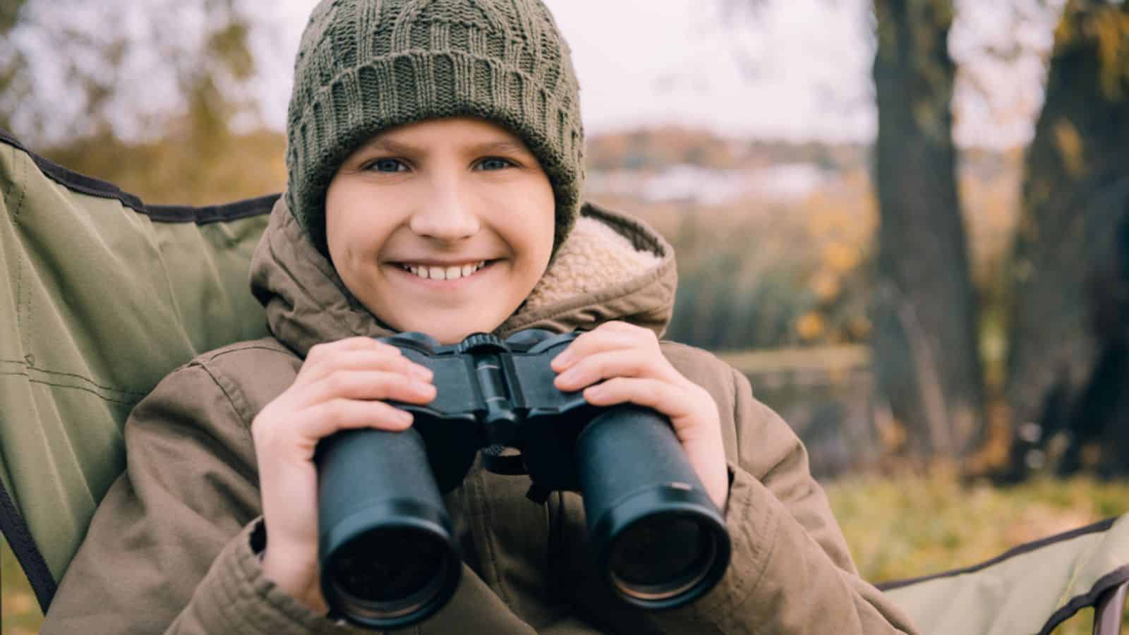 Kid looking at camera and holding binoculars