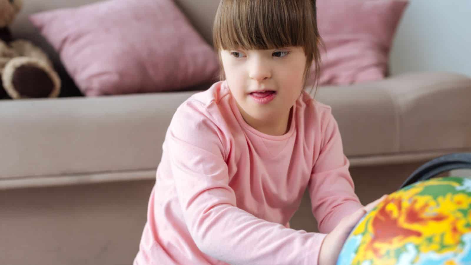 Kid with down syndrome playing with globe