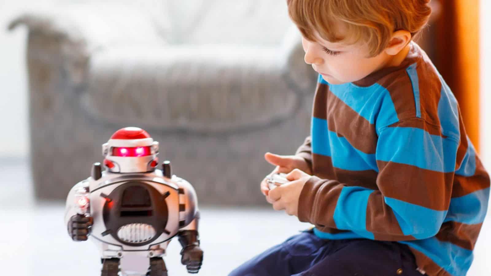 Little blond boy playing with robot toy at home, indoor