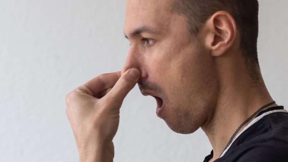 Man smells something stinky and pinches his nose