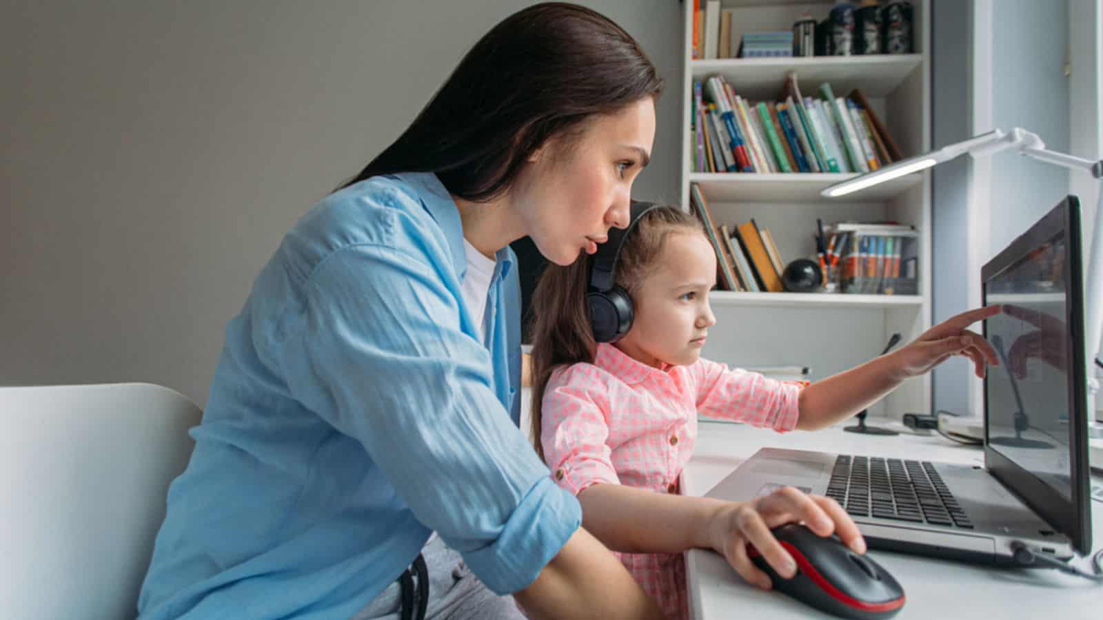 Mom and daughter are at home using laptop