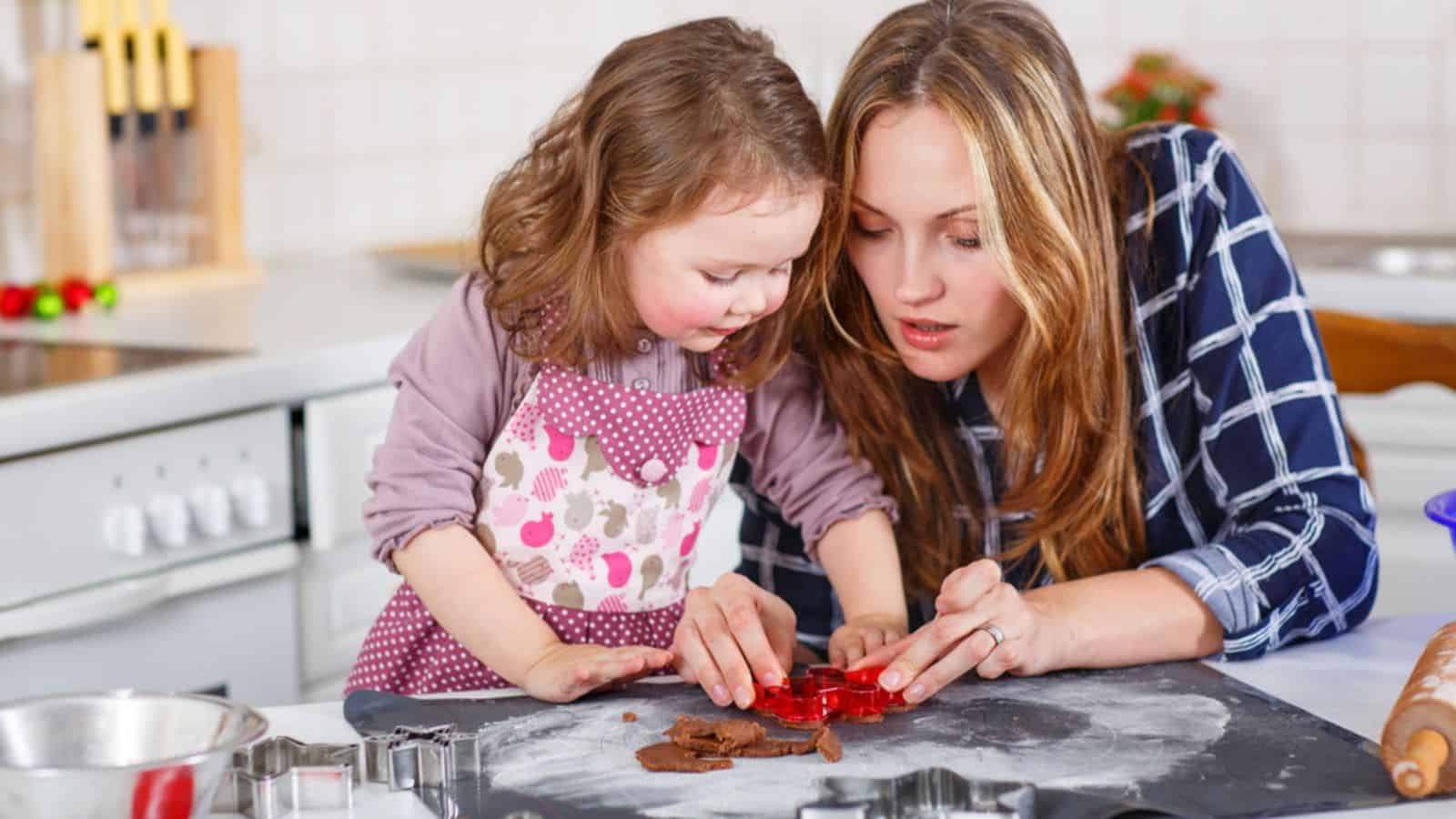 Mother and little kid girl baking gingerbread cookies for Christmas